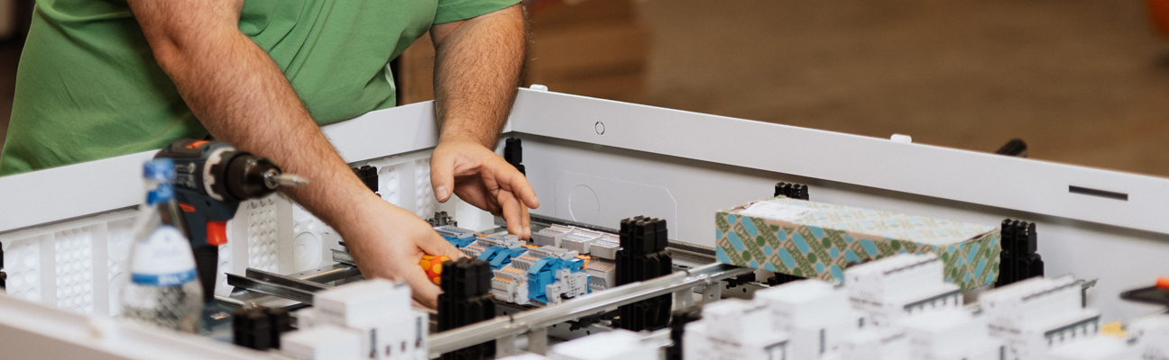 Hände, die an einem Elektrokasten arbeiten.